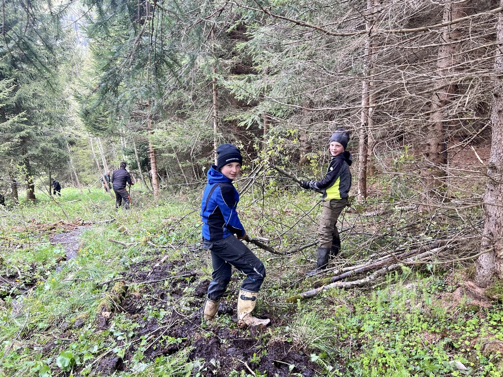 Zwei Kinder, die beim Ausschneiden eines Wildbachs mithelfen