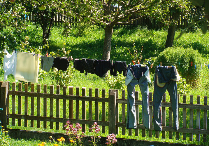 Wäsche ist auf einer Wäscheleine aufgehängt vor einem Zaun.