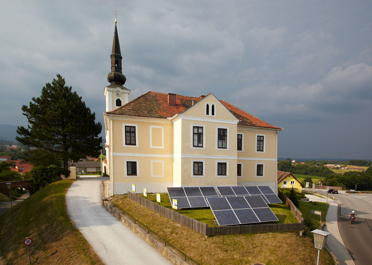 Kirche mit Solarpanelen auf davorliegender Wiese